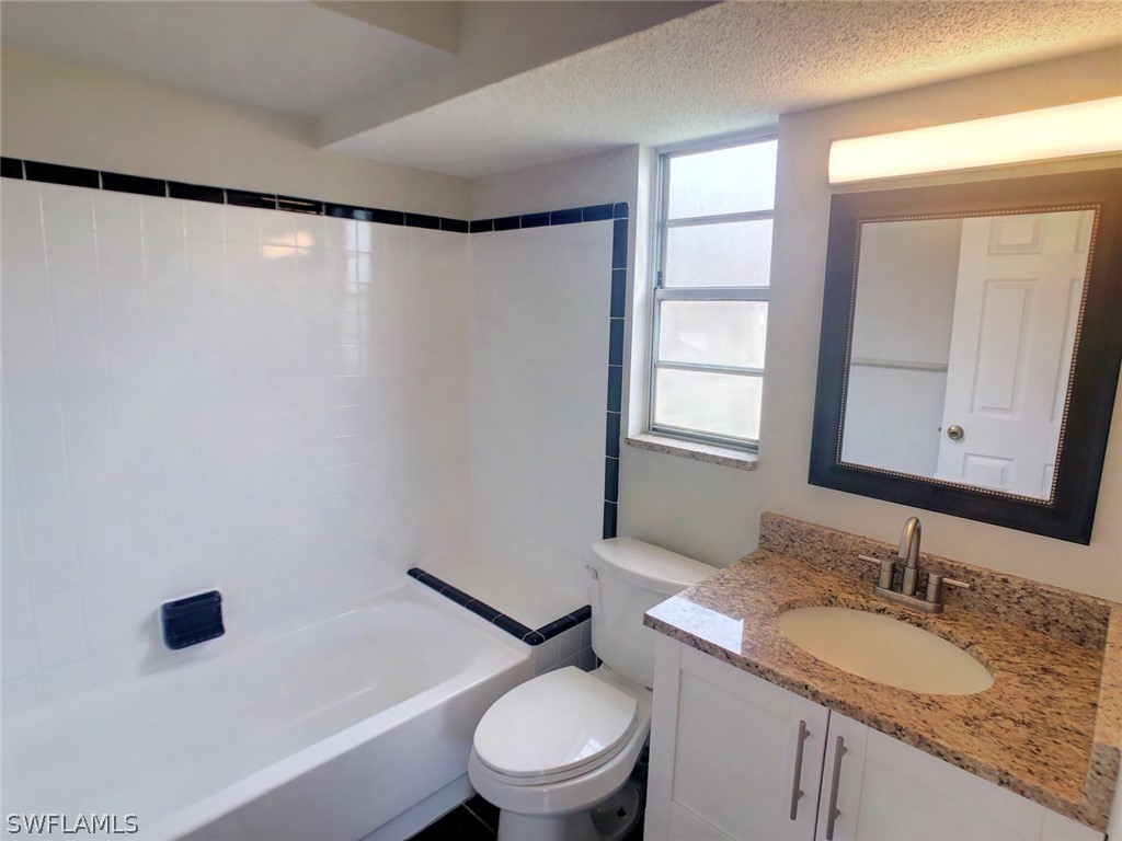 18577 Iris Road Fort Myers, FL 33967 - Photo 9 of 16 a bathroom with a granite countertop sink toilet a mirror and shower