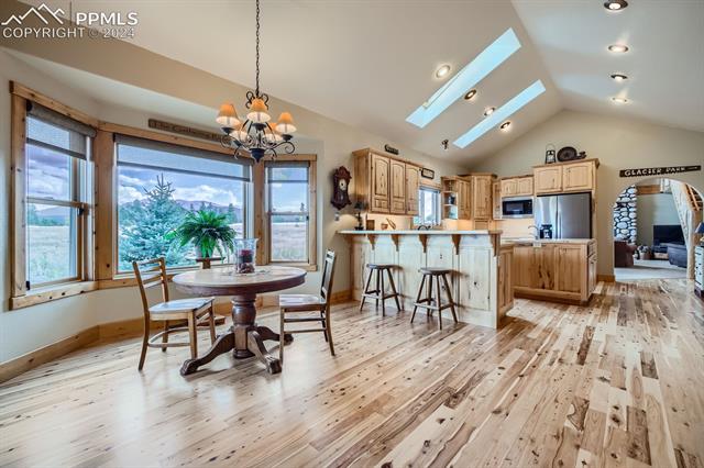 182 Joshua Road Divide, CO 80814 - Photo 9 of 35 Dining room with an inviting chandelier, light hardwood / wood-style floors, and lofted ceiling with skylight