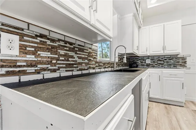 a view of a livingroom with wooden floor a ceiling fan and windows