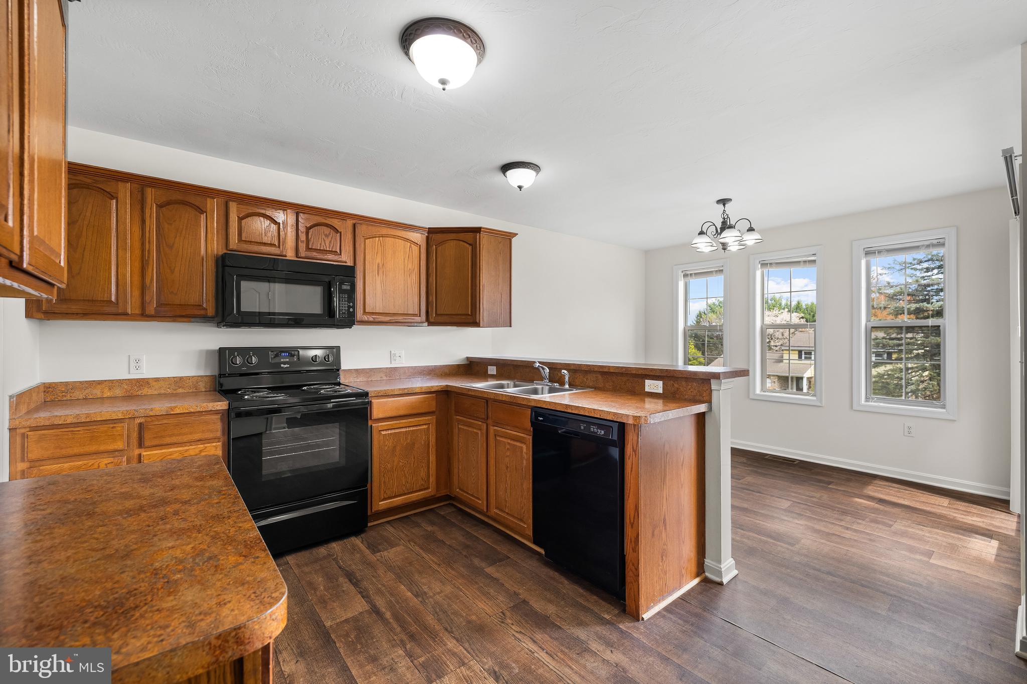 34 Shady Tree Court York, PA 17402 - Photo 5 of 22 a kitchen with stainless steel appliances granite countertop a stove top oven a sink dishwasher a refrigerator and a microwave oven with wooden floor