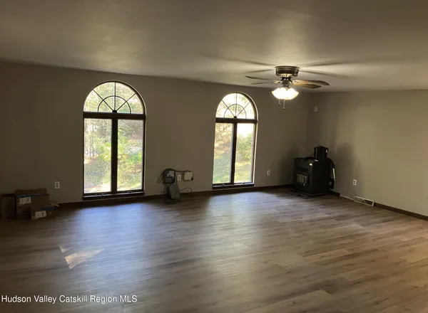 a view of empty room with wooden floor and fan