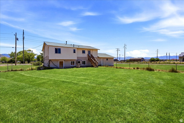 1613 Sunset Road Lake Point, UT 84074 - Photo 29 of 33 Expansive green lawn with a white exterior structure featuring a green metal roof and a wooden exterior staircase