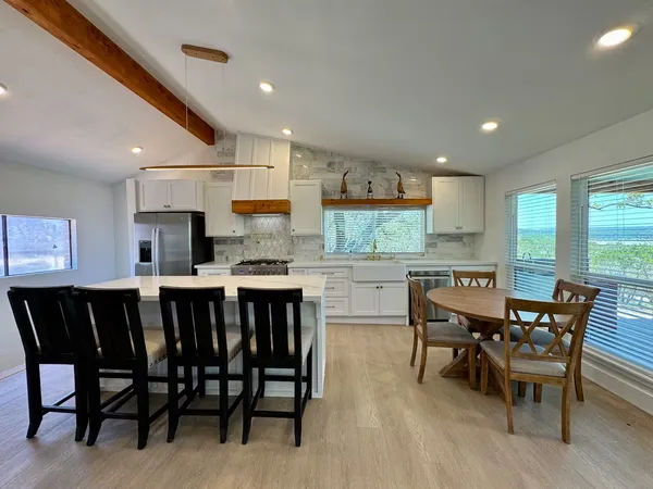 a kitchen with stainless steel appliances granite countertop a table chairs sink and cabinets
