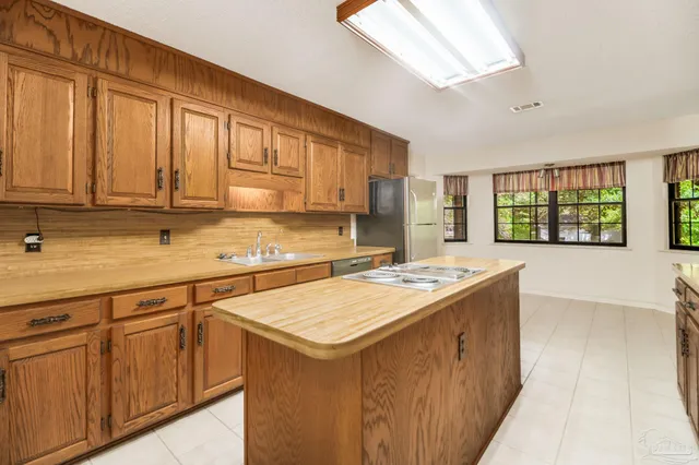 a large kitchen with stainless steel appliances a large counter top a stove and a refrigerator
