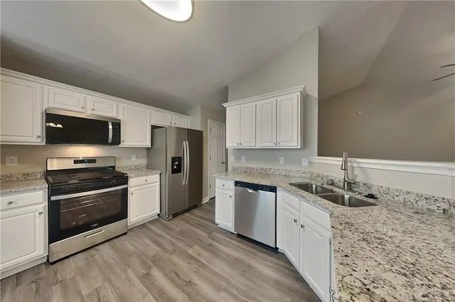 a kitchen with stainless steel appliances granite countertop a sink and a stove top oven with wooden floor