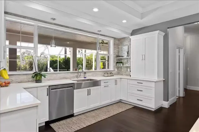a large white kitchen with granite countertop a large window and white stainless steel appliances
