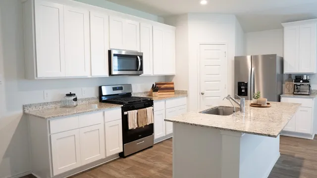 a kitchen with stainless steel appliances granite countertop a sink stove refrigerator and microwave with wooden floor