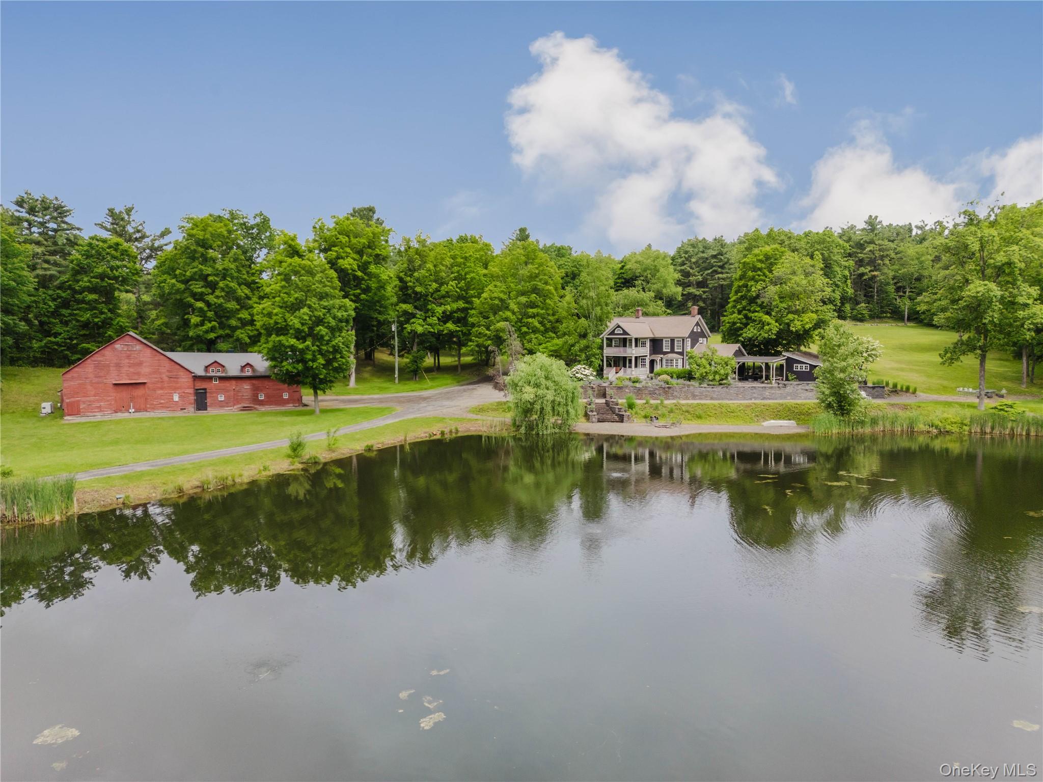 Water view with a barn and a heavily wooded area