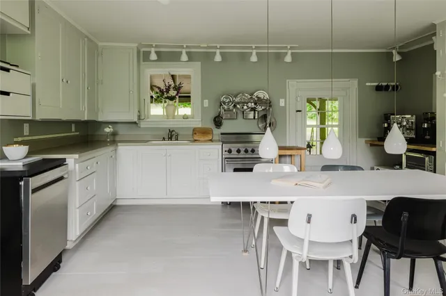 a kitchen with stainless steel appliances a white table chairs and a refrigerator