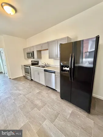 a kitchen with granite countertop a refrigerator and a stove top oven