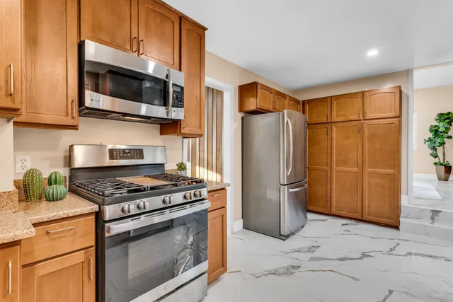 a kitchen with stainless steel appliances granite countertop a stove a refrigerator and a microwave