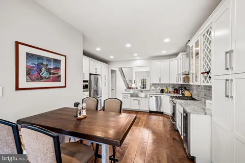 a view of a kitchen with kitchen island a stove a refrigerator a sink dishwasher with a dining table and chairs with wooden floor
