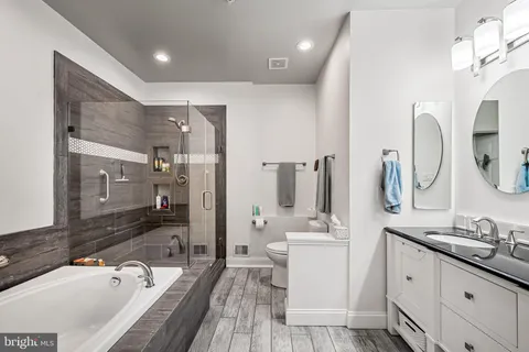 a bathroom with a granite countertop double vanity sink a mirror and a bathtub