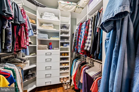 a view of walk in closet with clothes and shoes