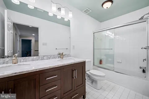 a bathroom with a granite countertop sink toilet a large mirror a shower and vanity