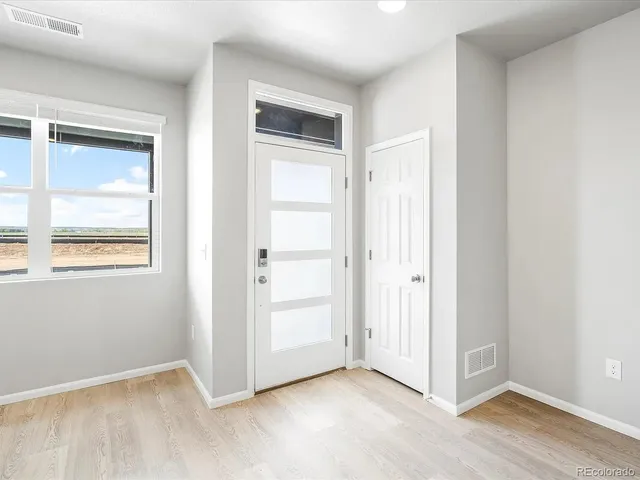 a view of kitchen and empty room with wooden floor