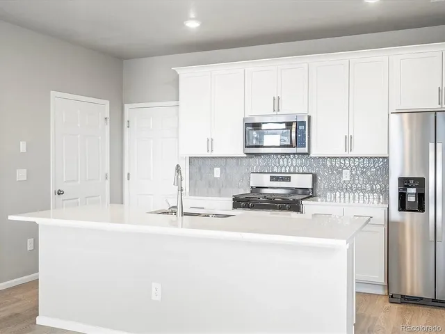 a kitchen with a sink stove top oven and refrigerator