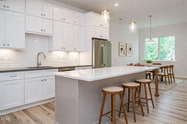 a kitchen with stainless steel appliances granite countertop a table chairs sink and cabinets
