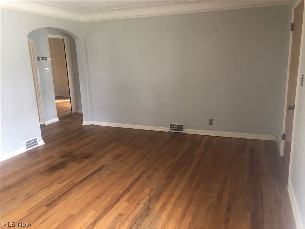 4037 Wilmington Road Cleveland, OH 44121 - Photo 6 of 36 Empty room featuring crown molding, arched walkways, and dark wood-type flooring