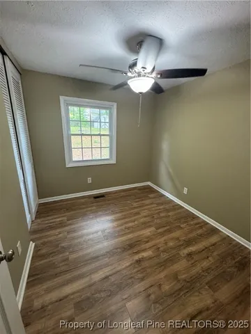 en empty room with wooden floor fan and window