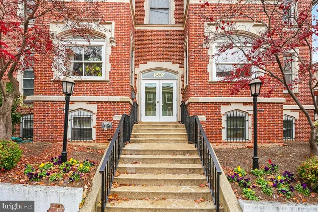 a front view of a multi story residential apartment building with a garden