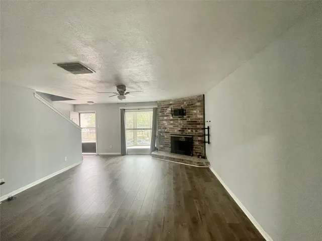 a view of a livingroom with wooden floor a ceiling fan and staircase