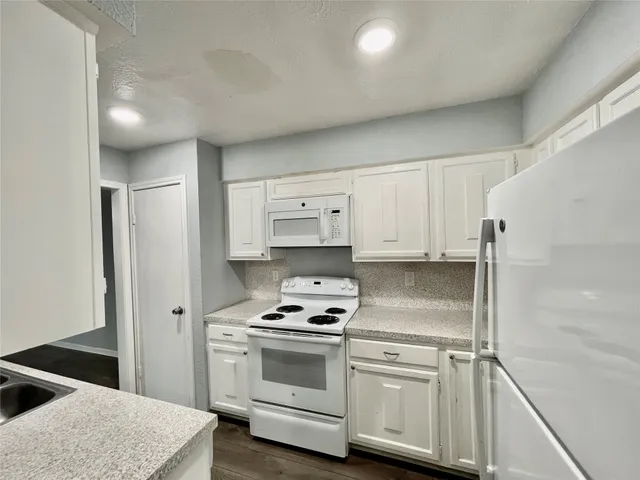 a kitchen with white cabinets and white appliances