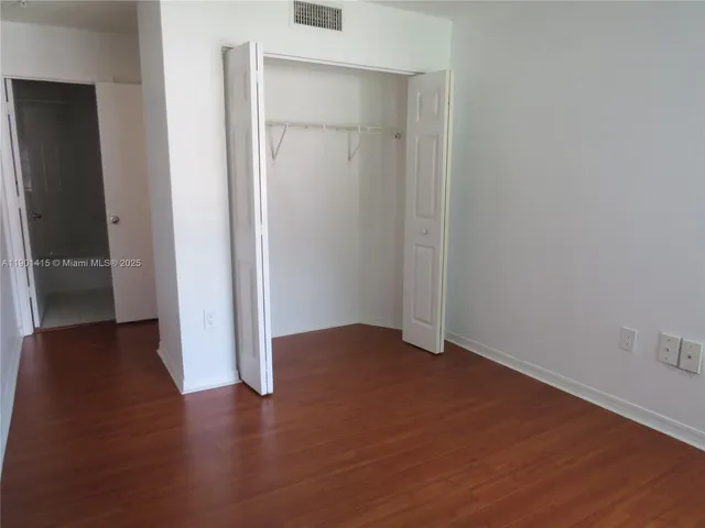 an empty room with wooden floor and closet