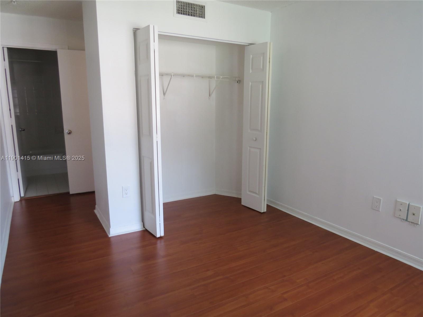 an empty room with wooden floor and closet