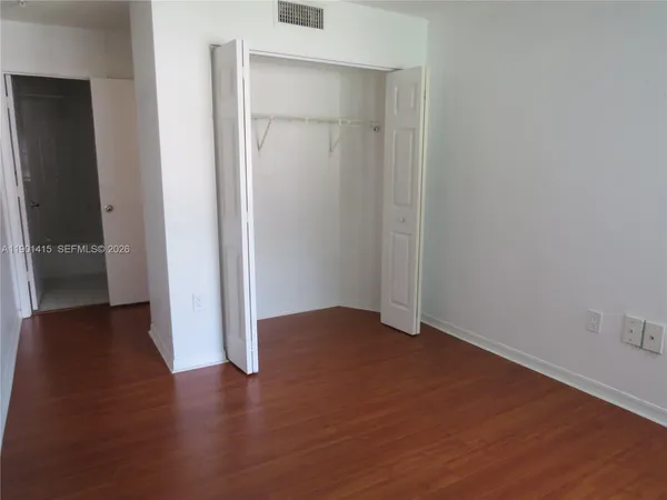 an empty room with wooden floor and closet