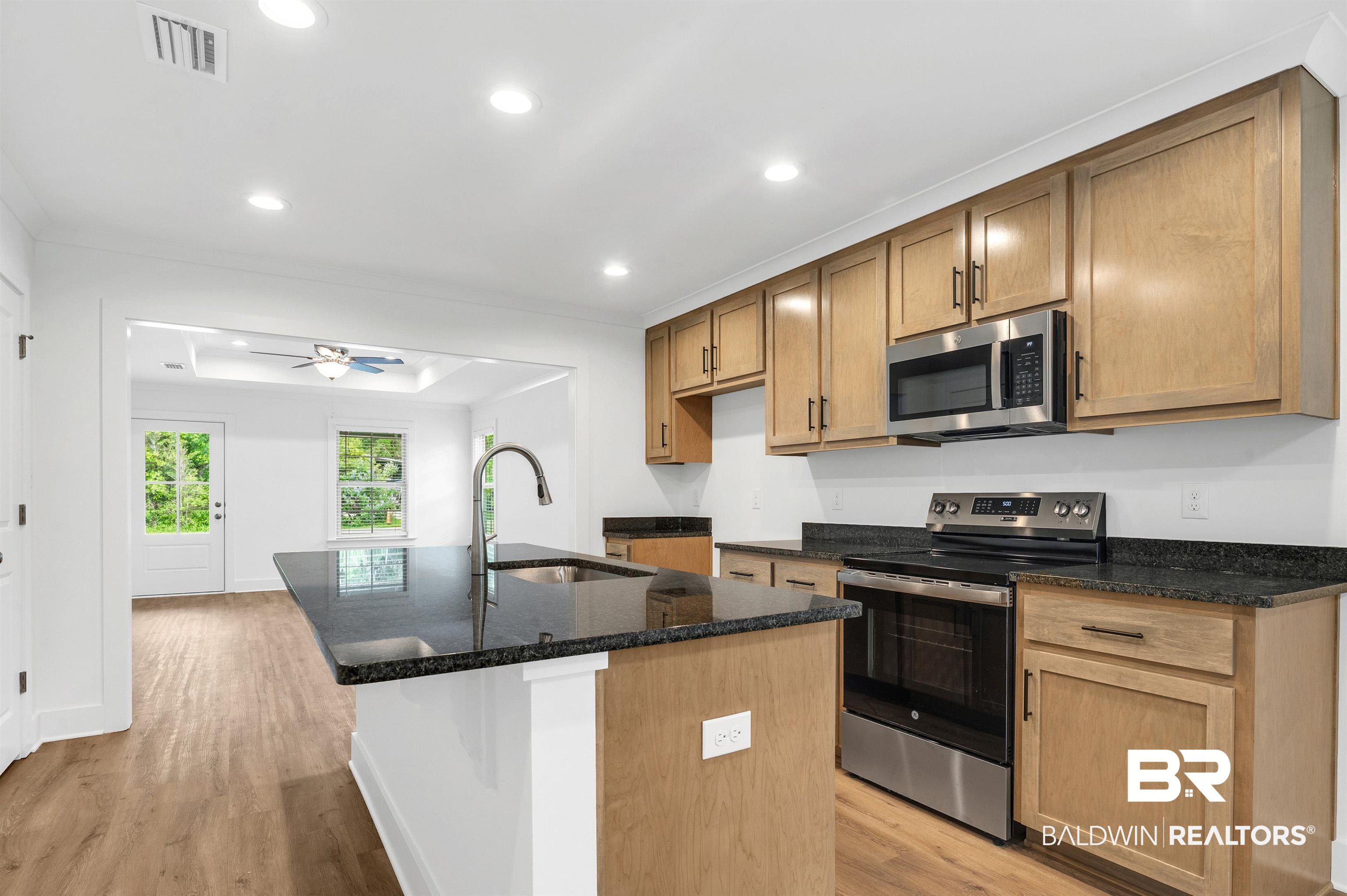 22045 8th Street Silverhill, AL 36576 - Photo 14 of 39 Kitchen featuring appliances with stainless steel finishes, a sink, light wood finished floors, dark stone countertops, and a kitchen island with sink