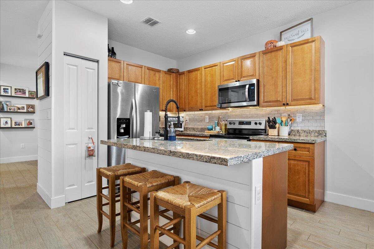 6013 Pine Tree Way Riviera Beach, FL 33410 - Photo 3 of 33 a kitchen with stainless steel appliances granite countertop a stove top oven a sink a refrigerator white cabinets and wooden floor