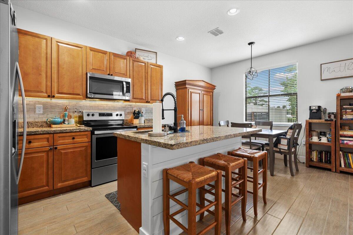 6013 Pine Tree Way Riviera Beach, FL 33410 - Photo 4 of 33 a kitchen with stainless steel appliances granite countertop a stove top oven a sink dishwasher a dining table and chairs with wooden floor