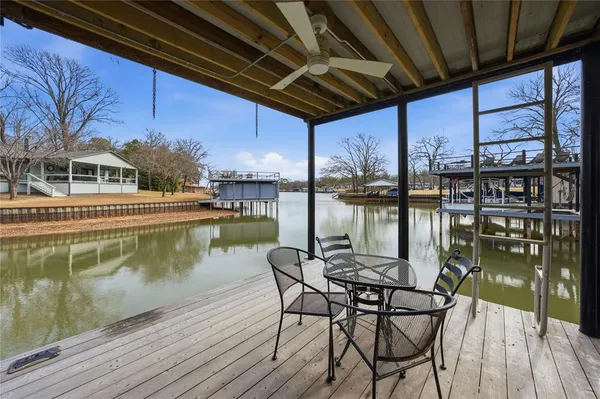 a view of a lake with a table chairs and wooden floor