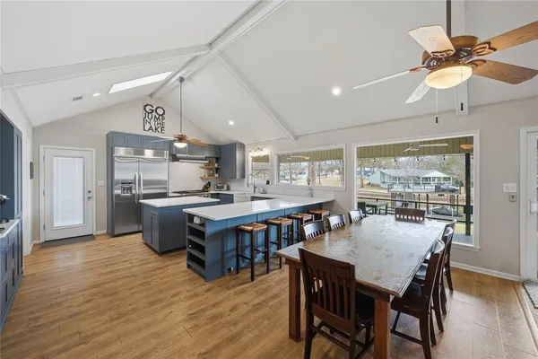 a dining room with stainless steel appliances kitchen island a table chairs and a refrigerator