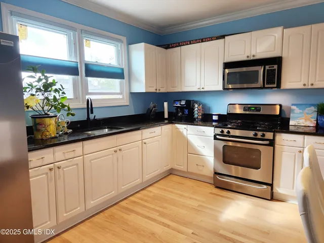 a kitchen with granite countertop white cabinets and white appliances