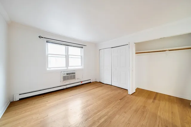 an empty room with wooden floor closet and windows