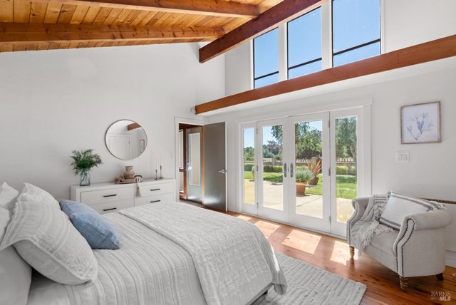 a bedroom with a large bed and wooden floor