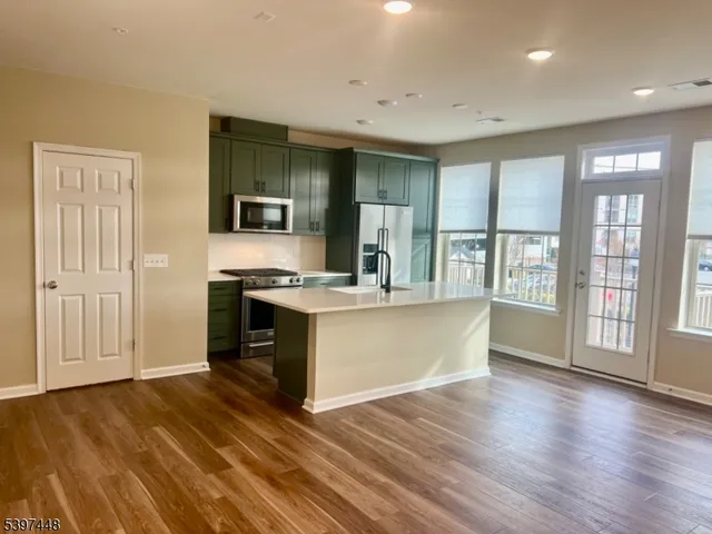 a large kitchen with stainless steel appliances granite countertop a large stove top oven and couches