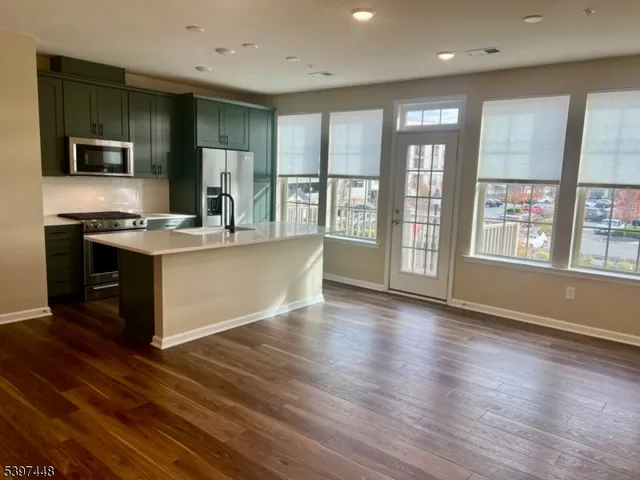 an open kitchen with kitchen island wooden floor and stainless steel appliances