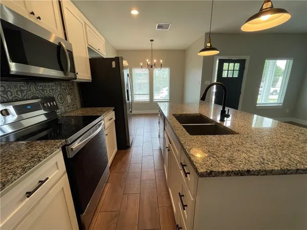 a kitchen with granite countertop a sink a counter top space cabinets and stainless steel appliances