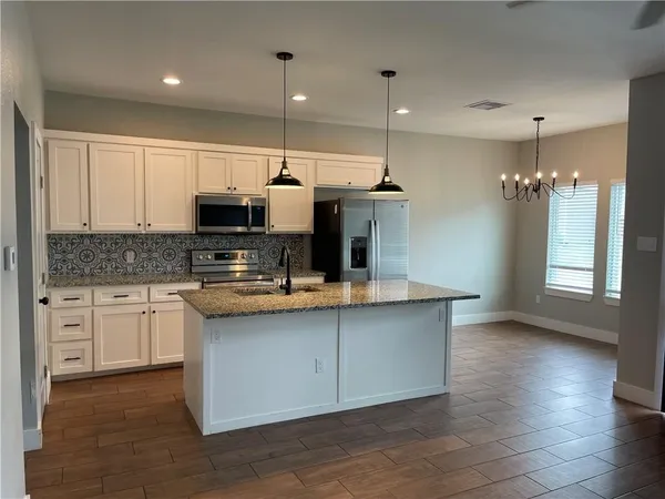 a kitchen with kitchen island granite countertop a sink cabinets and stainless steel appliances