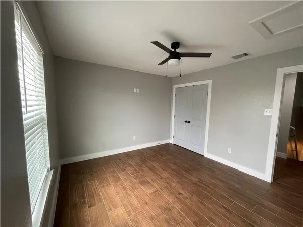 a view of empty room with wooden floor and fan