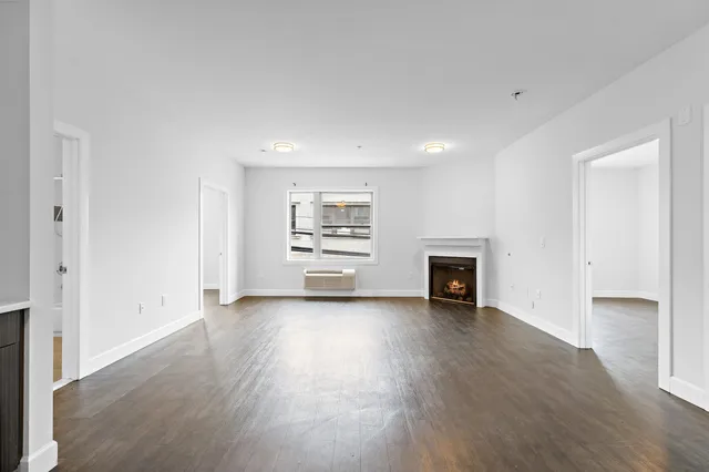 an empty room with fireplace and wooden floor