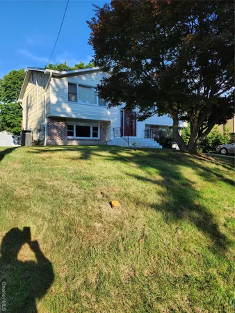 a view of a house with a big yard and large trees