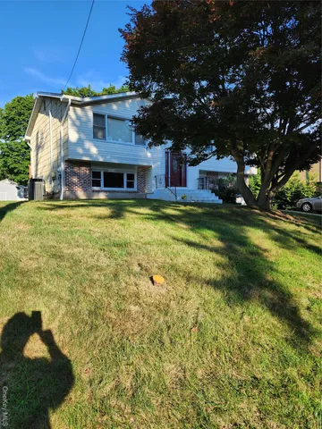 a view of a house with a big yard and large trees