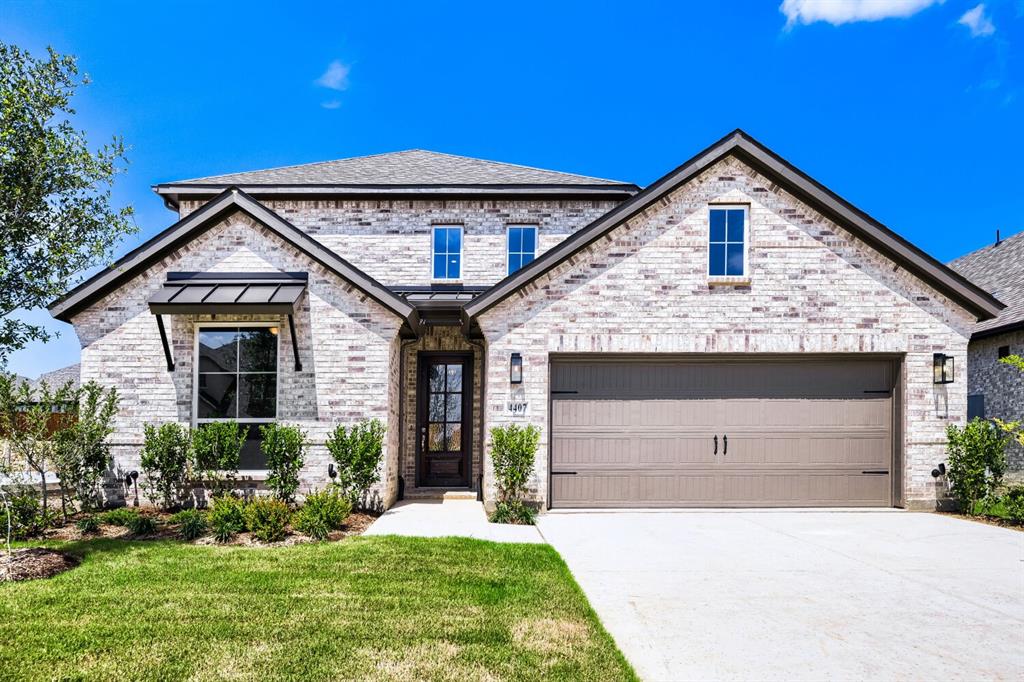 4407 Windy Point Road Oak Point, TX 75068 - Photo 1 of 27 Two-story brick facade residence featuring a two-car garage, covered entry, and decorative window awnings