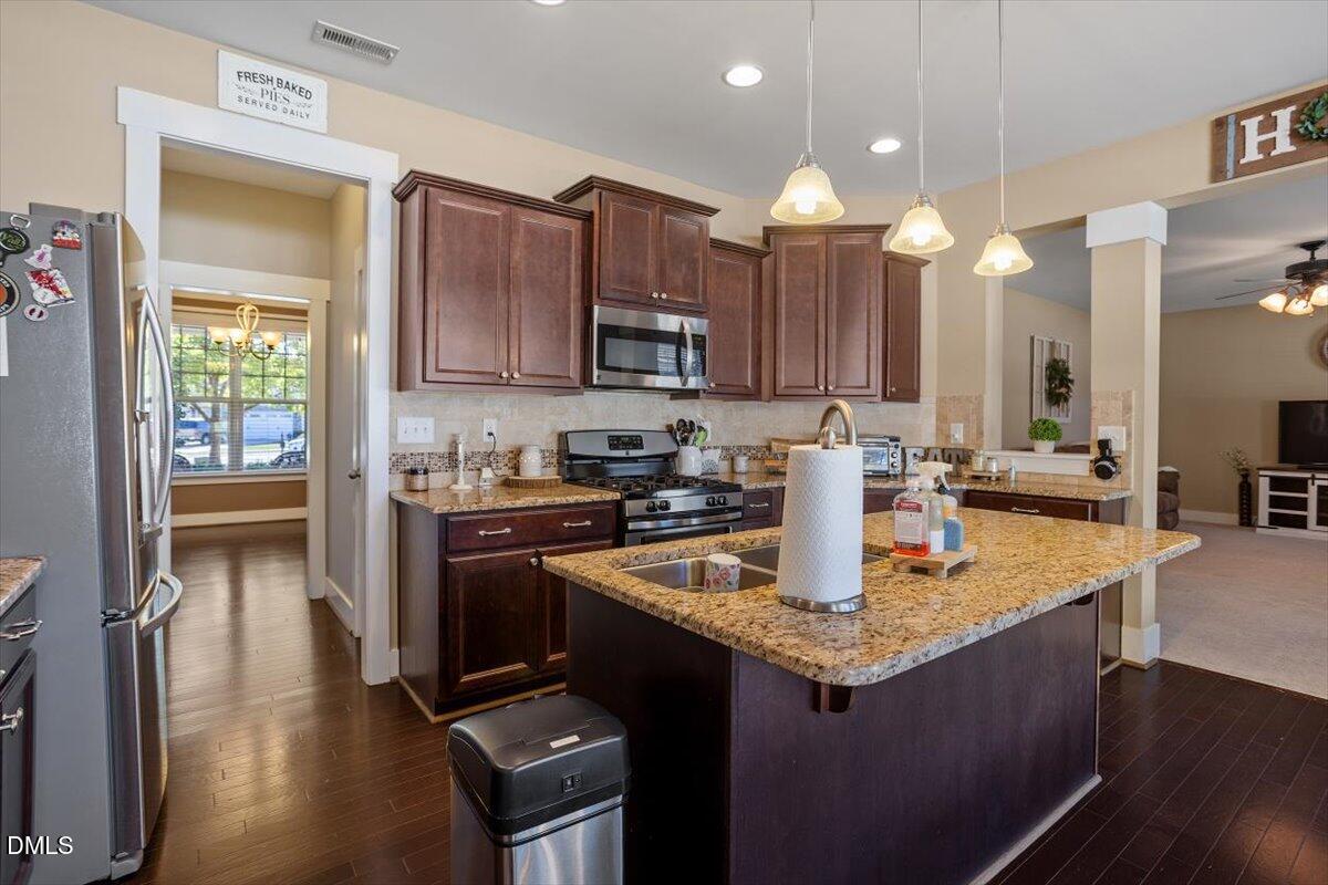 4222 Vineyard Ridge Drive Zebulon, NC 27597 - Photo 11 of 39 a kitchen with kitchen island granite countertop a stove top oven a sink dishwasher and cabinets with wooden floor