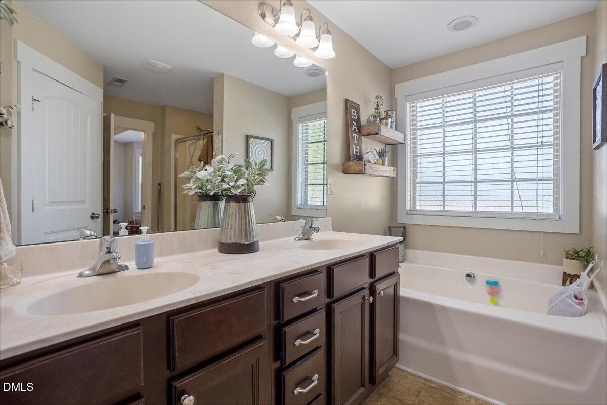 4222 Vineyard Ridge Drive Zebulon, NC 27597 - Photo 16 of 39 a bathroom with a granite countertop sink a large mirror a bathtub and next to a window