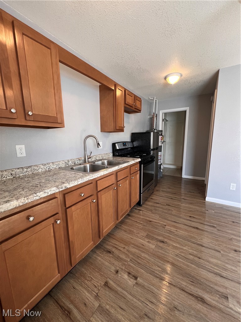 1724 Youngstown Kingsville Road, Unit 4 Vienna, OH 44473 - Photo 6 of 11 Kitchen featuring dark wood finished floors, stove, a textured ceiling, a sink, and brown cabinets